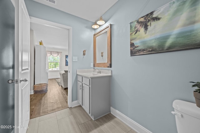 bathroom with vanity, toilet, and baseboards