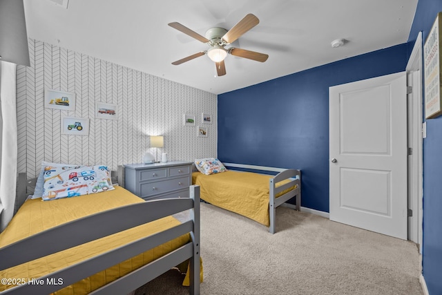 bedroom with a ceiling fan, wallpapered walls, carpet, baseboards, and an accent wall