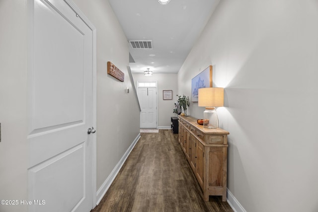 corridor featuring visible vents, baseboards, and dark wood-style floors