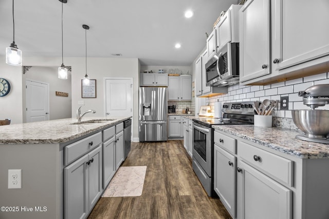 kitchen with a sink, tasteful backsplash, an island with sink, dark wood-style flooring, and appliances with stainless steel finishes