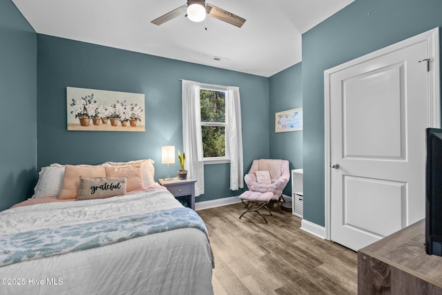 bedroom featuring baseboards, visible vents, ceiling fan, and wood finished floors