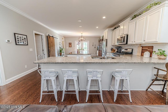 22 Calhoun Ln, Pinehurst, NC 28374 - kitchen featuring appliances with stainless steel finishes, ornamental molding, white cabinets, a breakfast bar, and a peninsula