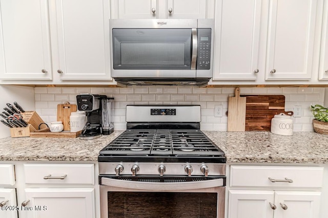 22 Calhoun Ln, Pinehurst, NC 28374 - kitchen featuring appliances with stainless steel finishes, white cabinetry, tasteful backsplash, and light stone countertops