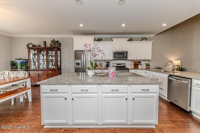 22 Calhoun Ln, Pinehurst, NC 28374 - kitchen with stainless steel appliances, a sink, white cabinets, ornamental molding, and a center island with sink