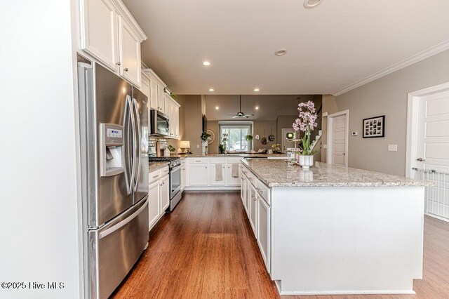 22 Calhoun Ln, Pinehurst, NC 28374 - kitchen featuring stainless steel appliances, wood finished floors, a peninsula, white cabinets, and crown molding