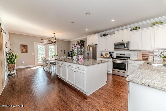 22 Calhoun Ln, Pinehurst, NC 28374 - kitchen with appliances with stainless steel finishes, a sink, white cabinetry, ornamental molding, and a center island