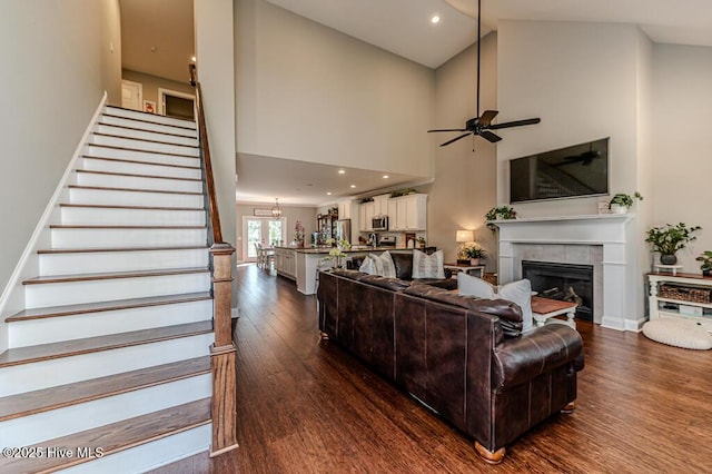 22 Calhoun Ln, Pinehurst, NC 28374 - living area featuring dark wood-type flooring, a ceiling fan, a tile fireplace, stairway, and high vaulted ceiling