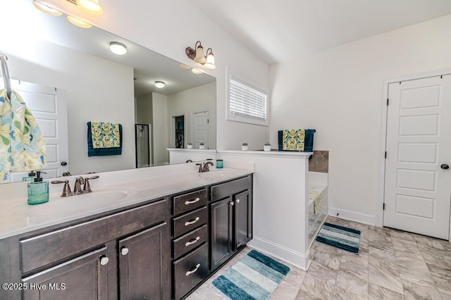 full bath with a sink, baseboards, a garden tub, and double vanity