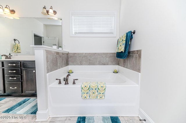 full bathroom featuring vanity, baseboards, and a bath