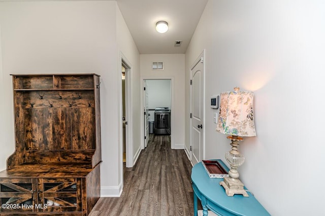 hall with baseboards, visible vents, washer and clothes dryer, and wood finished floors