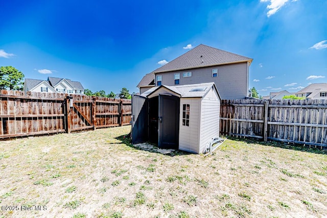 rear view of house with a storage shed, a gate, an outdoor structure, and a fenced backyard