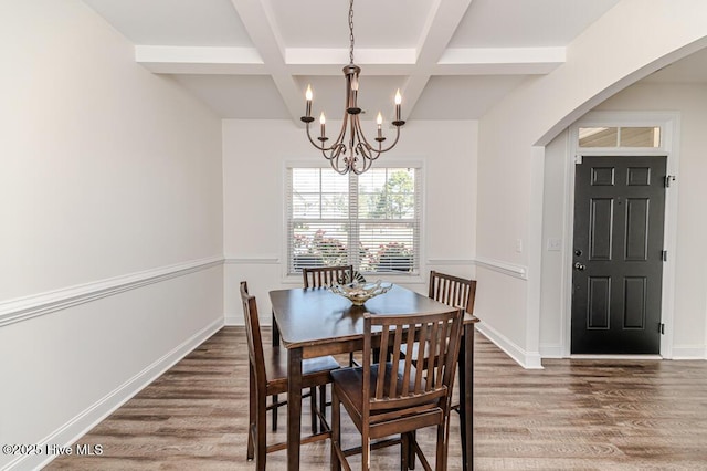 dining room with an inviting chandelier, arched walkways, wood finished floors, beamed ceiling, and coffered ceiling
