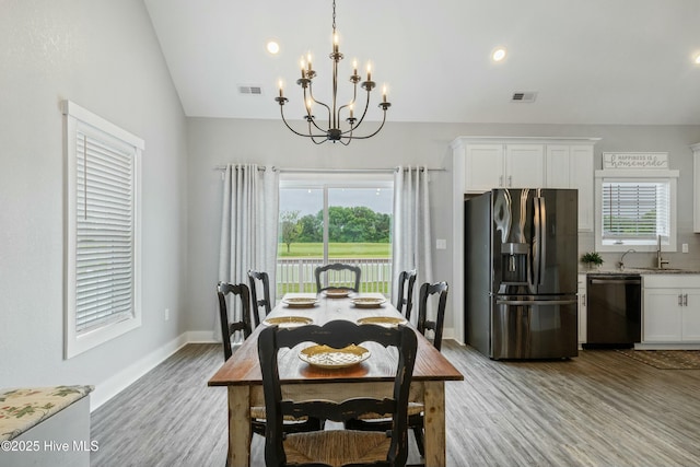144 Pelican Pointe Dr, Elizabeth City, NC 27909 - dining space featuring a notable chandelier, vaulted ceiling, visible vents, and light wood-style flooring