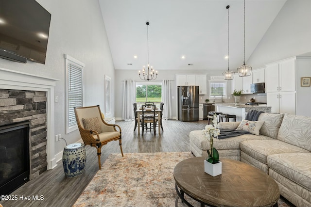 144 Pelican Pointe Dr, Elizabeth City, NC 27909 - living room featuring an inviting chandelier, high vaulted ceiling, a stone fireplace, and wood finished floors