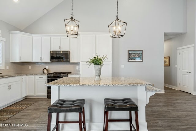 144 Pelican Pointe Dr, Elizabeth City, NC 27909 - kitchen with a kitchen bar, high vaulted ceiling, white cabinets, and appliances with stainless steel finishes