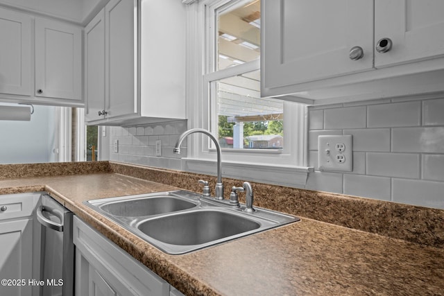 kitchen featuring a sink, dark countertops, decorative backsplash, and white cabinets