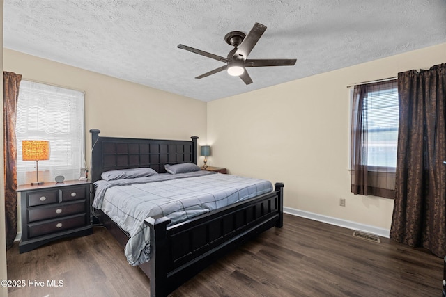 bedroom featuring visible vents, a textured ceiling, baseboards, and wood finished floors