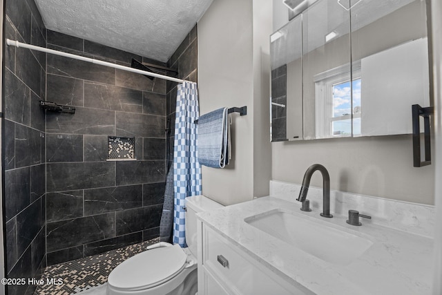 bathroom with vanity, a textured ceiling, toilet, and tiled shower