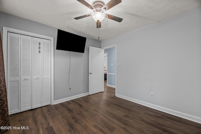 unfurnished bedroom featuring baseboards, a ceiling fan, wood finished floors, and a closet