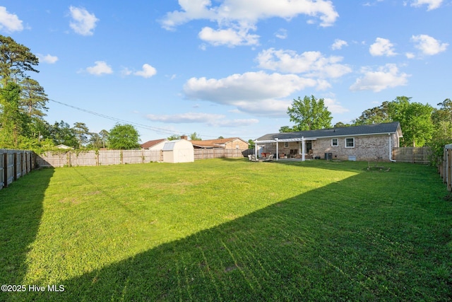 view of yard featuring a storage shed, an outdoor structure, and a fenced backyard