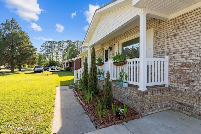 view of home's exterior with a porch, a lawn, and brick siding