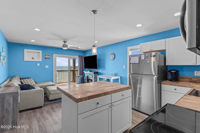 kitchen featuring wooden counters, freestanding refrigerator, open floor plan, light wood-style floors, and white cabinetry