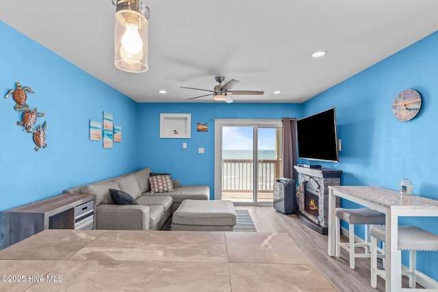 living room with a fireplace, a ceiling fan, recessed lighting, and wood finished floors