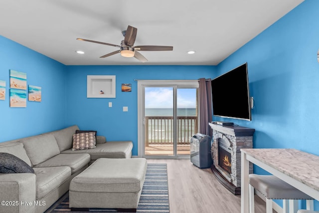 living area featuring recessed lighting, light wood-style flooring, ceiling fan, and a fireplace