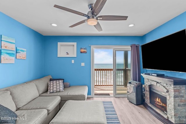living room featuring a ceiling fan, a fireplace, wood finished floors, baseboards, and recessed lighting