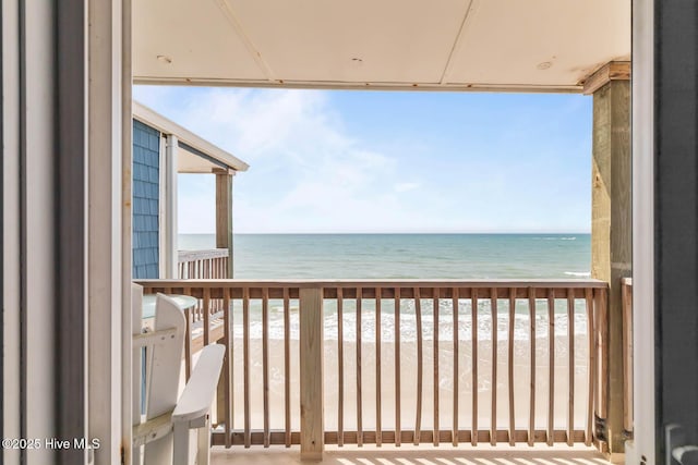 balcony with a water view and a view of the beach