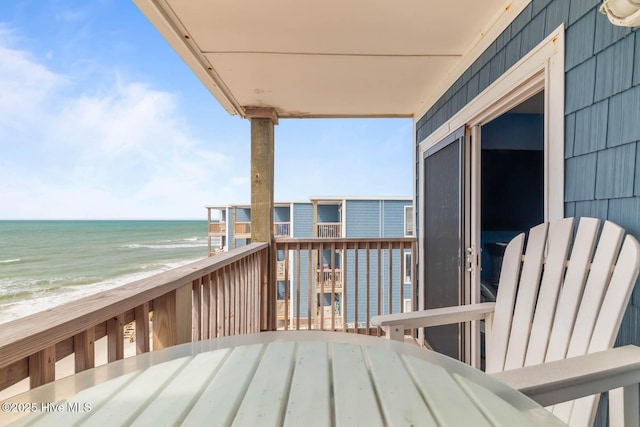 deck featuring a view of the beach, outdoor dining space, and a water view