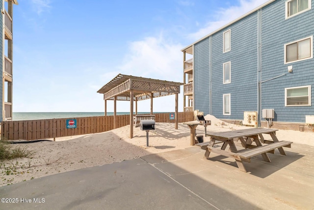 view of home's community with a pergola, fence, a water view, and a patio area