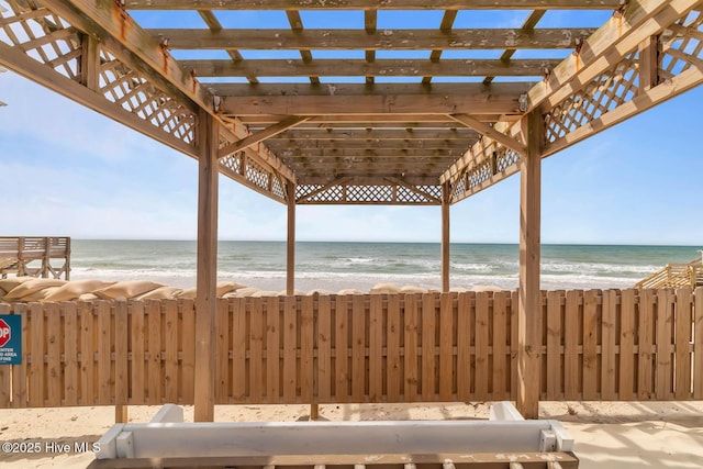view of patio / terrace with fence, a view of the beach, a pergola, and a water view