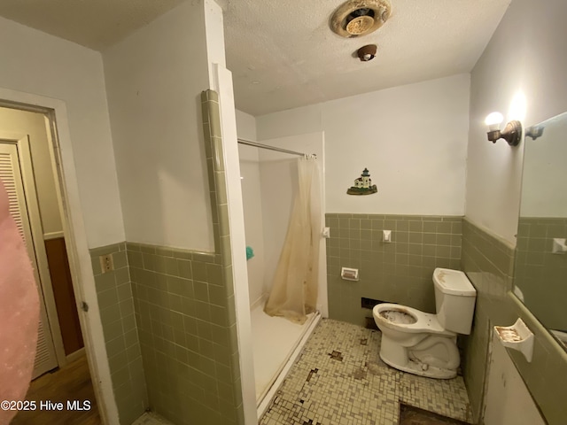 129 Cape Fear Dr, Southport, NC 28461 - full bath with tile walls, a wainscoted wall, a shower stall, toilet, and tile patterned flooring