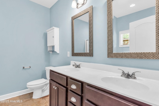 full bathroom featuring toilet, baseboards, and double vanity
