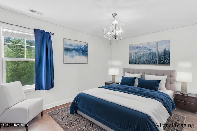 bedroom with wood finished floors, a chandelier, and baseboards