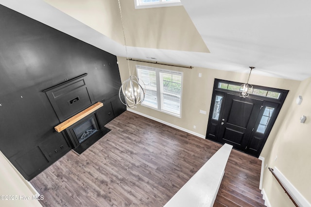 entryway featuring wood finished floors, a chandelier, plenty of natural light, and baseboards