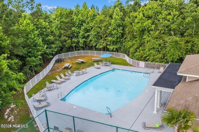 community pool featuring fence, a patio area, and view of scattered trees