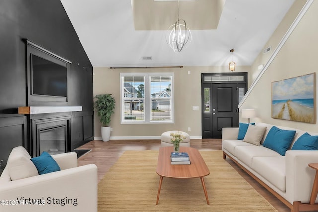 living room with vaulted ceiling, a chandelier, wood finished floors, and baseboards