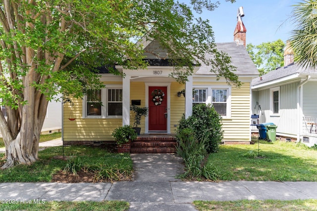 bungalow-style house featuring a chimney, a front yard, and crawl space
