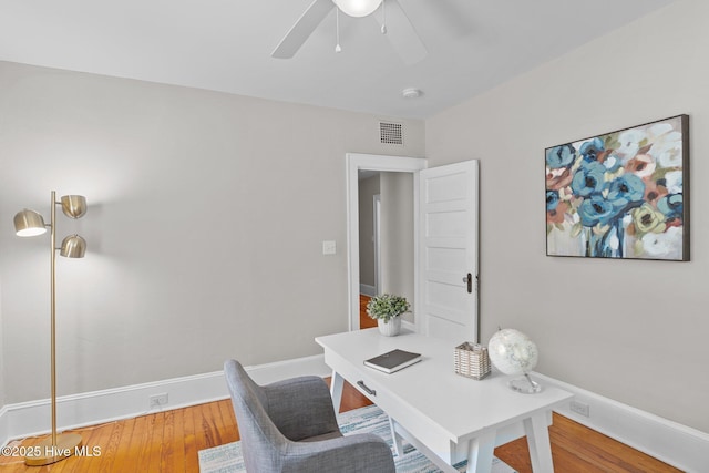 home office featuring visible vents, a ceiling fan, baseboards, and wood finished floors