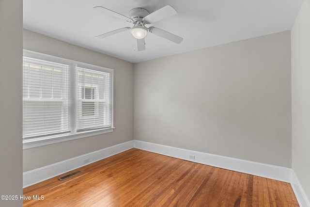 spare room with baseboards, a ceiling fan, visible vents, and light wood-type flooring