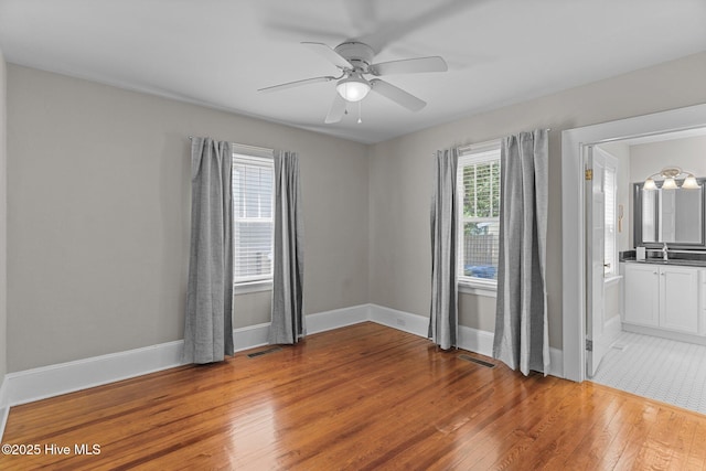 spare room with visible vents, light wood-style flooring, ceiling fan, and baseboards