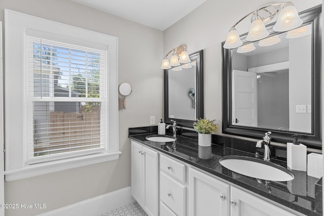 bathroom with double vanity, a sink, baseboards, and tile patterned floors