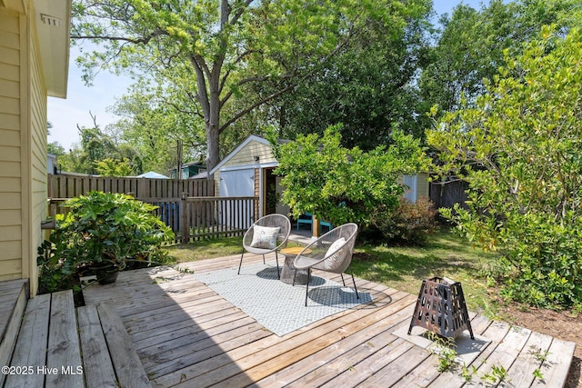deck featuring an outdoor structure, a fenced backyard, and a storage shed