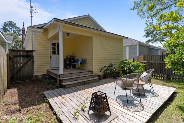 rear view of property featuring a gate, fence, and a deck