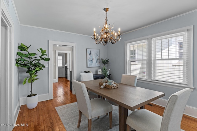 dining area featuring baseboards, an inviting chandelier, ornamental molding, and wood finished floors