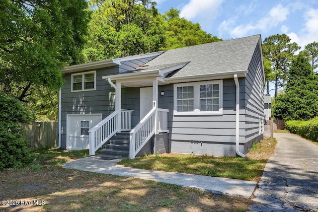 tri-level home featuring fence and roof with shingles