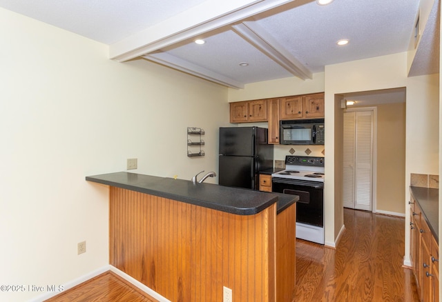 250 Sugar Gum Ln Unit 156, Pinehurst, NC 28374 - kitchen featuring a peninsula, wood finished floors, dark countertops, and black appliances