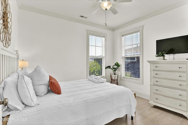 bedroom with crown molding, light wood finished floors, a ceiling fan, baseboards, and visible vents